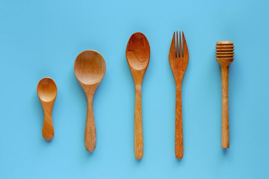 Wooden spoon, fork and honey dipper on blue background for kitchen utensils concept