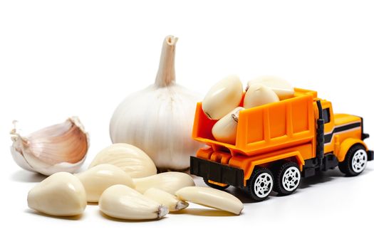 A yellow toy dump truck with garlic on white background for food and transportation concept