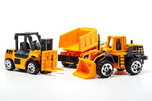 A yellow toy heavy machinery includes dump truck, bulldozer and forklift on white background for vehicle and transportation concept