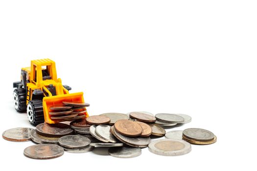 A yellow toy bulldozer with stack of coins on white background for saving money, investment, business and finance concept