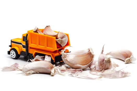 A yellow toy dump truck with garlic on white background for food and transportation concept