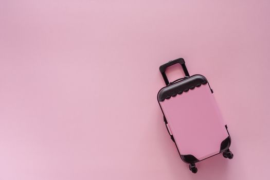 Mini pinky luggage toy model on pink pastel colored background for traveling concept