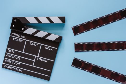 Movie clapper board with film on blue background for filming equipment