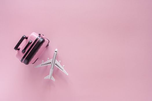 White airplane model with pinky luggage on pink background for travel and journey concept