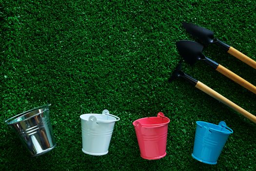 Gardening tools with tin pails or buckets on green grass background for planting concept