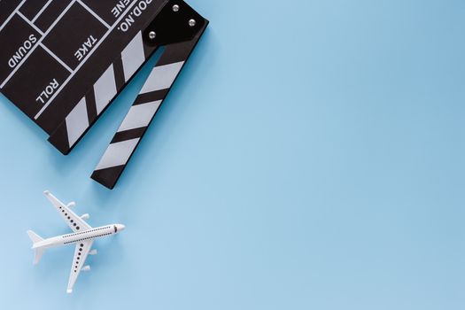 Movie clapper board with white airplane model on blue background