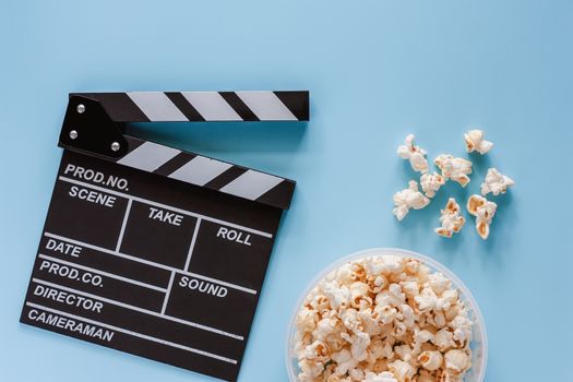 Movie clapper board with popcorn on blue background for entertainment concept