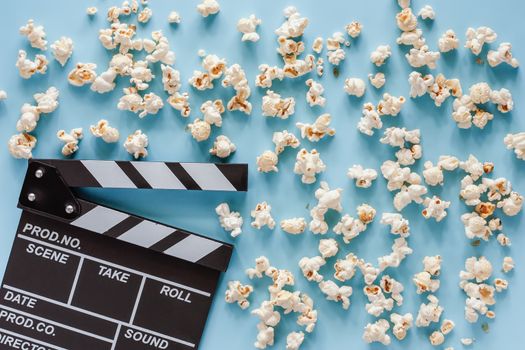 Movie clapper board with popcorn on blue background for entertainment concept