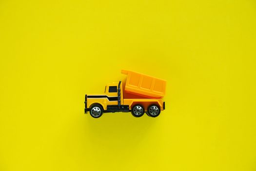 Mini toy dump truck on yellow background for vehicle and transportation concept