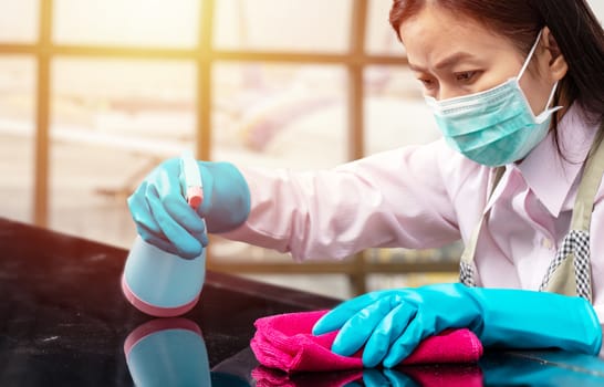 airport staff wearing hygienic face mask and blue rubber glove holding pink microfiber cleaning cloth and spray bottle with sterilizing solution make cleaning and disinfection for good hygiene around airport
