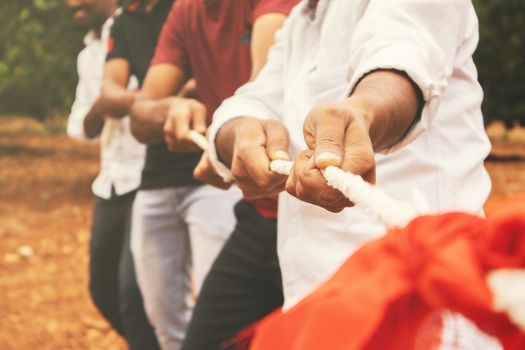 Close up of hands playing tug of war - Group of friends playing outdoor games in changing digital and technology world