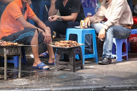 Editorial use only. Vietnamese men eating and drinking together on the sidewalk of the Old Quarter or French Quarter of Hanoi City in Vietnam
