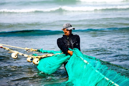 Editorial. A Vietnamese fisherman pulling the fishing nets back to shore in the fishing village of Quy Nhon, Vietnam