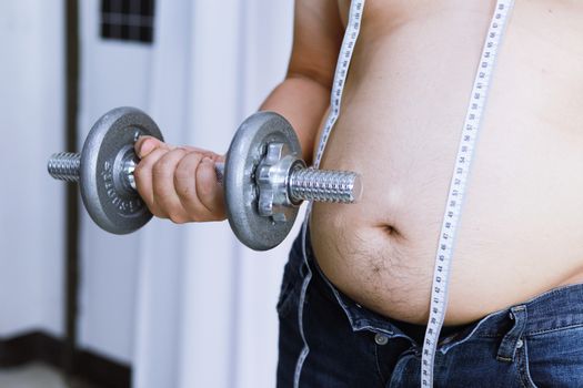 Overweight man exercising by lifting weight with a dumbbell