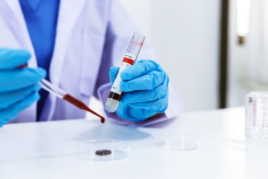 Scientist holding Coronavirus covid-19 infected blood sample tube. DNA testing of the blood in the laboratory with blood sample collection tubes and syringe Coronavirus Covid-19 vaccine research