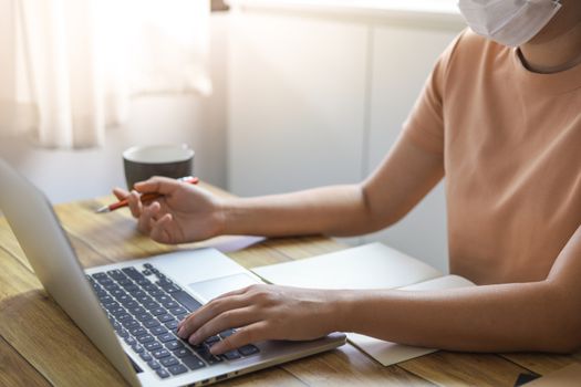 Woman working from home wearing protective mask. COVID-19 Pandemic Coronavirus home isolation auto quarantine wearing face mask protective for spreading of disease virus SARS-CoV-2. Working from home and Cleaning hands with sanitizer gel.