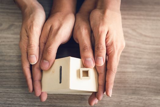 Couple Hands Holding Housing Model for Future Real Estate Saving, People Hand Joint to Protection Home Property Togetherness. House Insurance and Residential Loan Investment Concept.