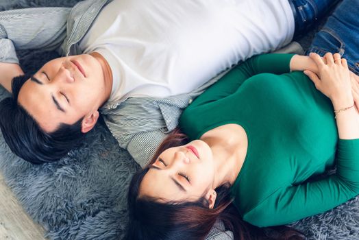 Young Couple Having Relaxing While Lying on Carpet at Their Home, Attractive Asian Couple Love are Relaxed Together on Living Room Flooring. Happy Moments and Lifestyles Concept