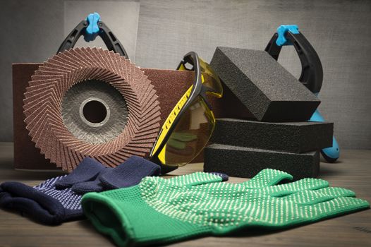 Different tools for sanding - sanding belt, clamps, abrasive sponge and flap disc for angle grinder, safety gloves and goggles, renovation, safety and health at work concept