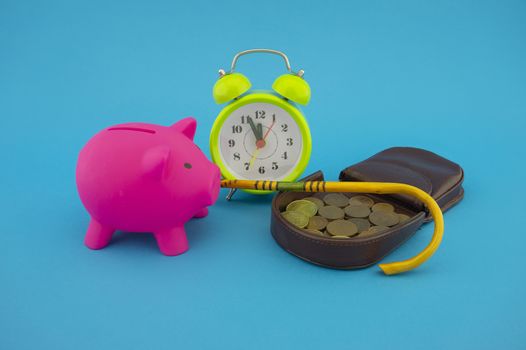 Saving for old-age and retirement concept with open purse with coins, walking stick, alarm clock and piggy bank over a blue background with copy space