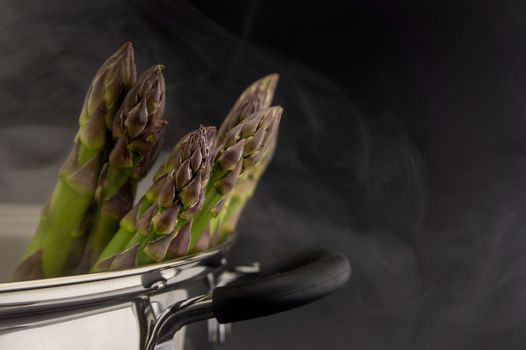 Fresh green asparagus spears in a metal pot with steam in close up conceptual of gourmet eating in spring