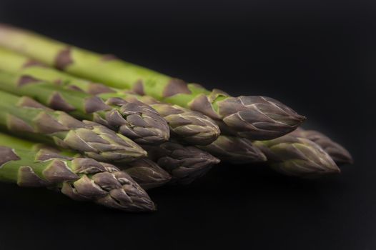 fresh raw green spring asparagus spears ready for cooking over a black background with copy space