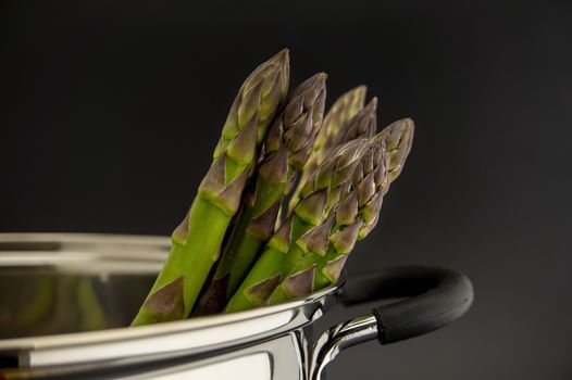 Fresh green asparagus spears in a metal pot with steam in close up conceptual of gourmet eating in spring