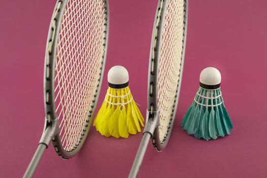 Badminton rackets and colorful feathered shuttlecocks in blue and yellow on punk background