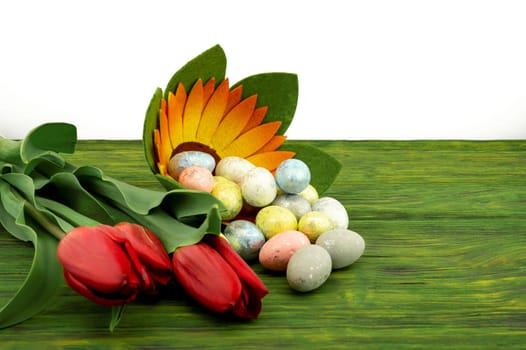 Easter background. Red spring tulips and painted eggs on vintage wooden board