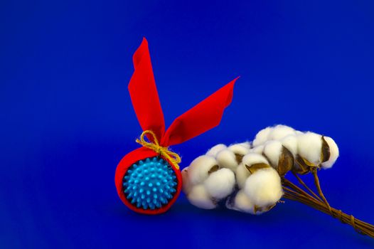 Corona virus molecule wrapped as gifts and natural cotton boll stems on a blue background with copy space