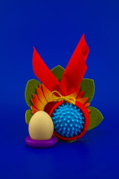 Close-up of Easter arrangement with eggs, flower and a Coronavirus or Covid-19 symbol on blue background for copy space