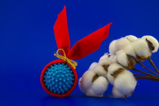 Corona virus molecule wrapped as gifts and natural cotton bolls on a blue background with copy space