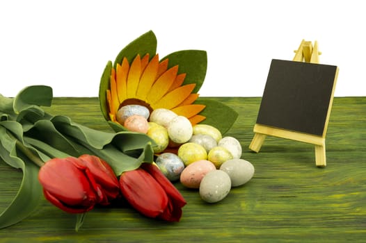 Easter background. Red spring tulips and painted eggs on vintage wooden board