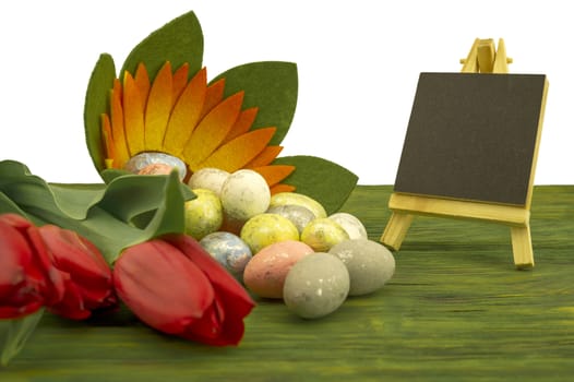 Easter background. Red spring tulips and painted eggs on vintage wooden board