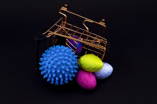 Blue virus molecule, shopping cart and creative colorful eggs made from yarn conceptual of the possibility of infection with corona virus or Covid-19 over a black background