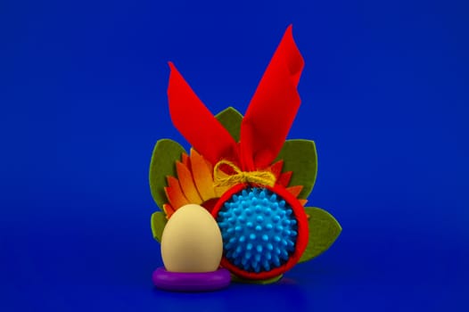 Close-up of Easter arrangement with eggs, flower and a Coronavirus or Covid-19 symbol on blue background for copy space