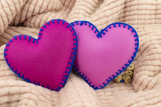 Hand stitched foam sheet toy hearts over a pink background for romantic, relationship, Valentines Day, broken heart love concept