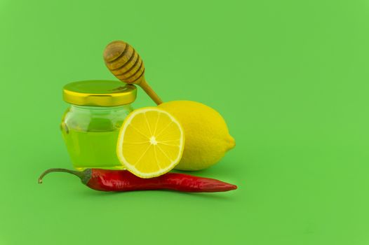 Ingredients for a healthy infusion with lemon, chili pepper and honey on green background, natural remedies for cold and flu season