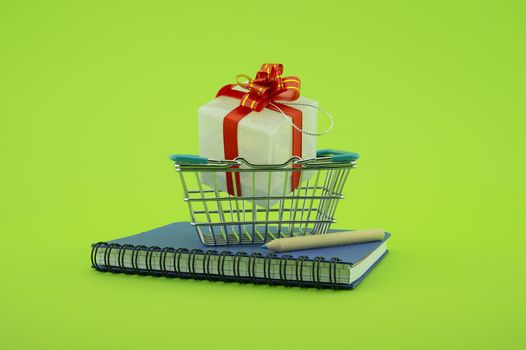 Diary or spiral bound notebook with shopping basket, pencil and gift with colorful red ribbon over green with copy space in a conceptual image