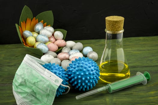 Virus pandemic and celebrating Easter concept with syringe and a protection mask, two blue virus molecules and glass container next to a Easter arrangement with traditional painted eggs