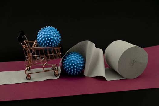 Corona virus or Covid-19 stockpiling of toilet paper or paper towel concept with a roll, shopping cart and two blue virus models over a red banner and dark background
