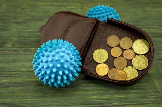 High-angle view of an open brown leather wallet full of golden coins next two blue virus molecules as concept for the covid-19 pandemy and the financial crisis