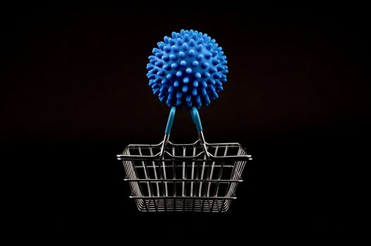 Blue virus molecule on a shopping basket conceptual of the possibility of infection with corona virus or Covid-19 over a black background