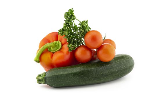 Green round courgette or zucchini, red pepper, cherry tomato twig and fresh parsley sprigs isolated on white background