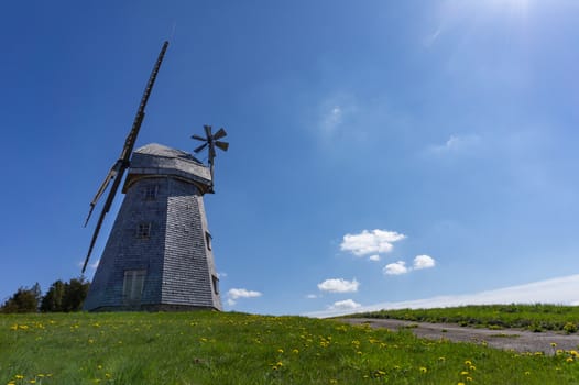 Historic windmill in a lush green field in spring against a sunny blue sky in a scenic landscape