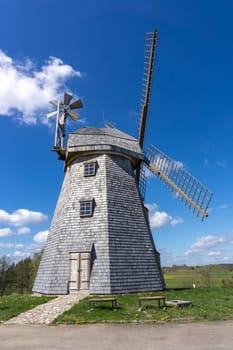 Historic windmill in a lush green field in spring against a sunny blue sky in a scenic landscape