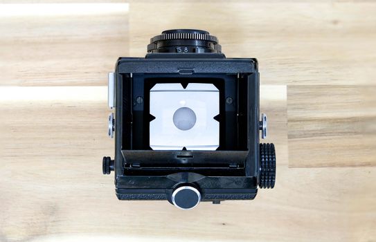 Top View of  Twin Lens Reflex Camera or TLR Film Camera  on Wooden Background with White Background on Focus Screen