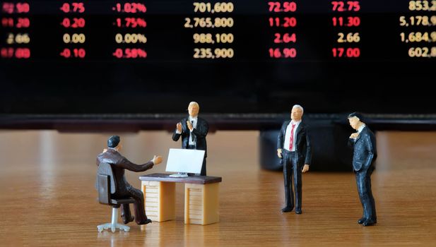 Miniature figure business people or Stock Trader looking at Blur Price Stock Ticker board for Graph Analysis