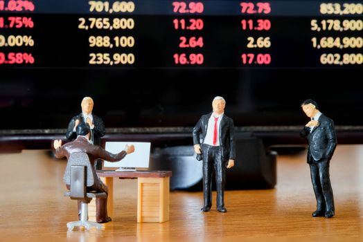 Miniature figure business people or Stock Trader looking at Blur Price Stock Ticker board for Graph Analysis
