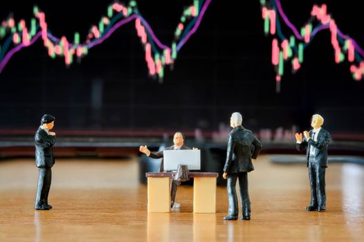 Miniature figure business people or Stock Trader meeting and consulting in front of Blur Price Stock graph board for Graph Analysis